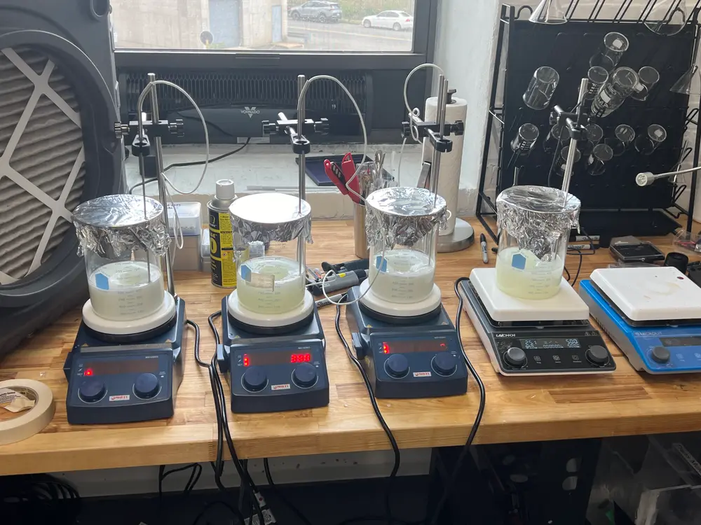 Foil-covered beakers stirring on a row of hot plates