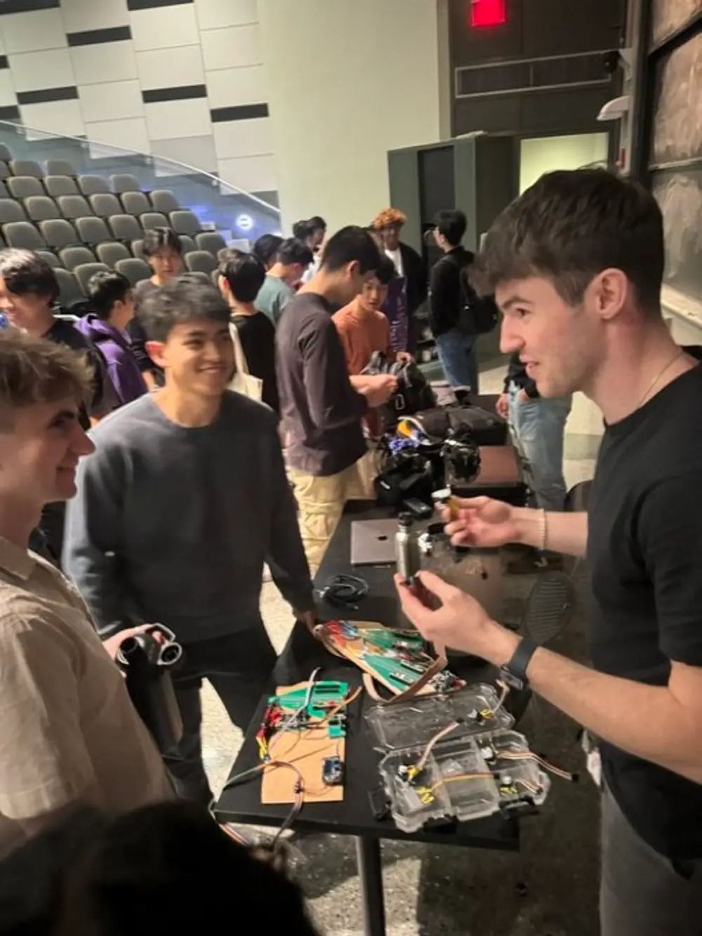 Showing prototype hardware to students at a lecture-hall table