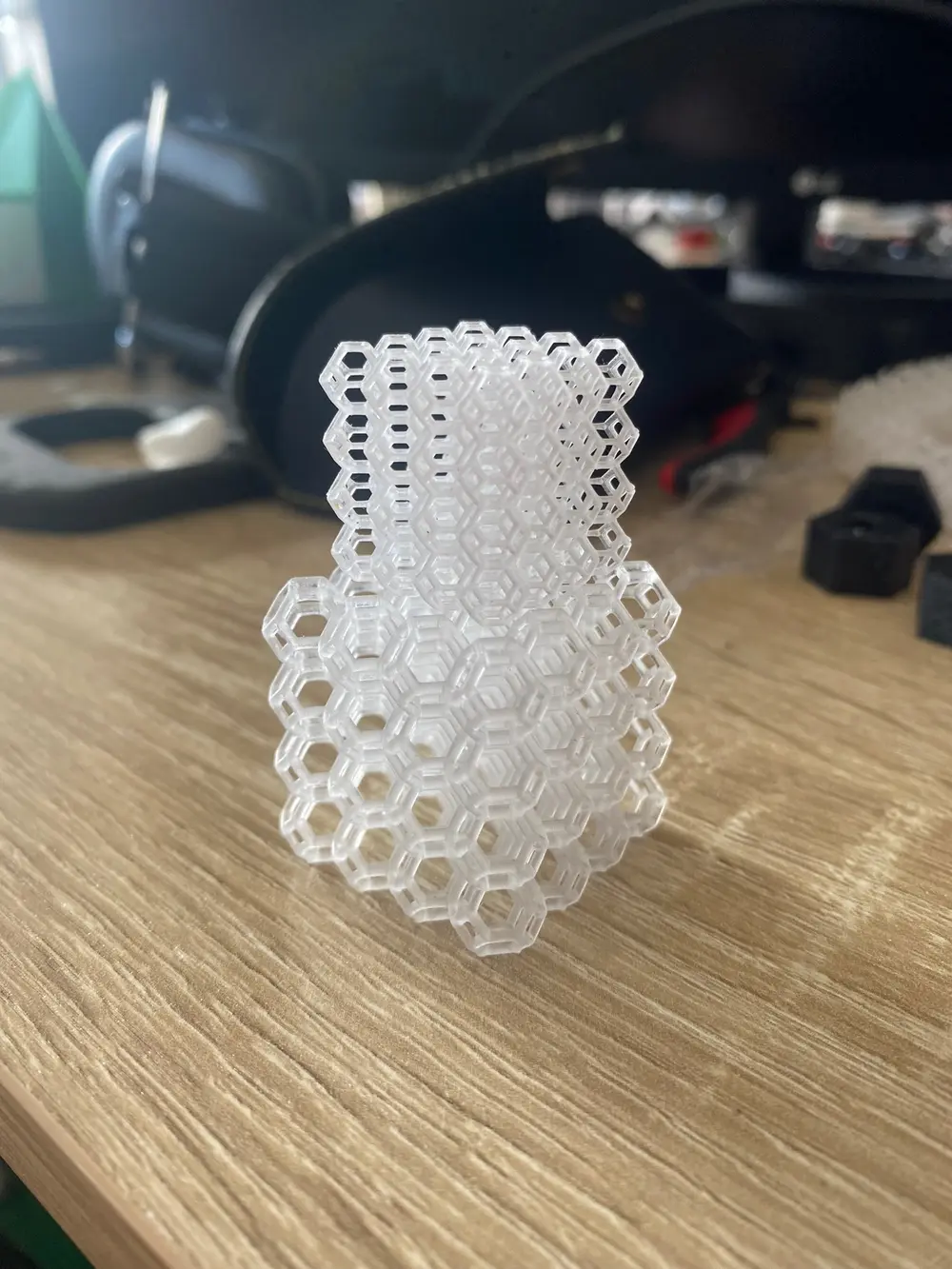 Clear 3D-printed hexagonal lattice standing on a wooden desk