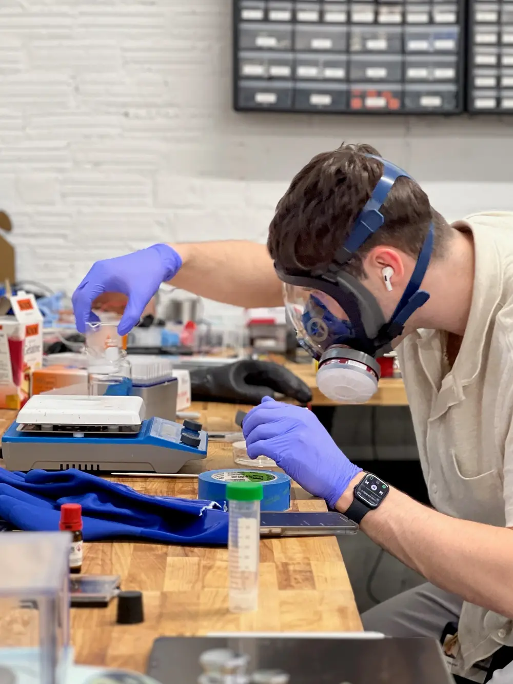 Working in a respirator and gloves beside a hot plate stirrer